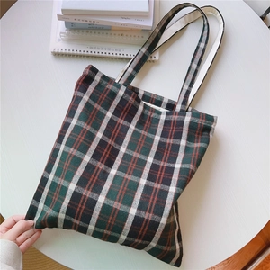 Detailansicht von oben: Karo-Stofftasche mit Büchern auf weißem Rundtisch