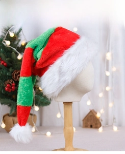 Detail of red and green striped plush Santa hat with a white pompom and festive background