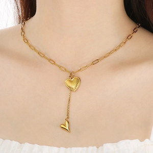 Detail of gold Y-shaped titanium steel necklace with layered heart pendants on a model