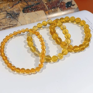 Macro view of four citrine crystal beaded bracelets in various sizes on a white background
