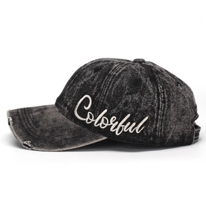 Detail of embroidered 'Colorful' logo on distressed grey washed denim baseball cap