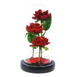 Preserved red roses in a glass dome with LED fairy lights on a black base