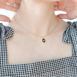 Gold stainless steel necklace featuring an oval black butterfly pendant on a model's neck
