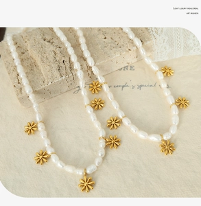Detailed close-up of natural white pearl necklace with delicate golden daisy charms