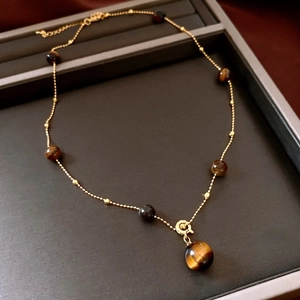 Detail of vintage gold bead chain with round tiger eye stones on jewelry tray