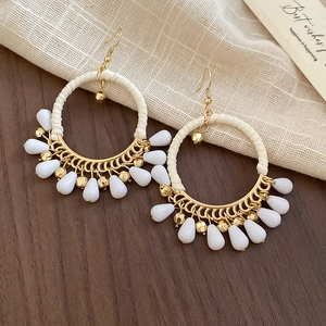 Macro detail of Bohemian gold hoop earrings with cream cotton wrap and teardrop beads