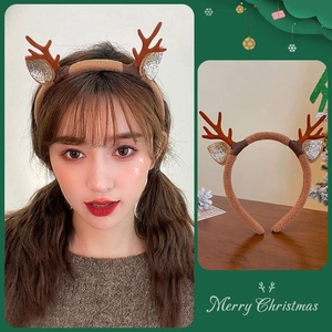 Detail view of brown plush reindeer antlers headband with festive Merry Christmas motifs