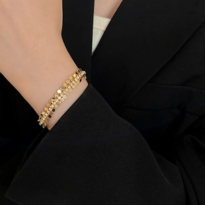 Détail d'un bracelet doré à paillettes multicouches avec strass sur une manche noire