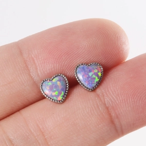 Piercing de langue cœur en argent avec opale violette irisée posé sur le bout du doigt