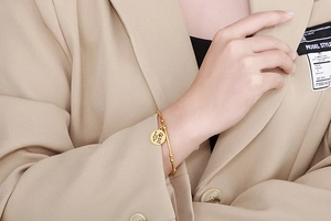 Detail of gold LOVE bangle with paw print charm worn on wrist for an elegant look