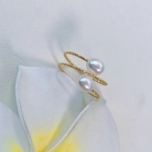 Macro detail of gold-filled twisted rope ring featuring two white freshwater pearls on a petal