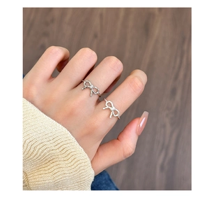 Detailed view of an elegant hollow twist bow ring in silver on a model's finger
