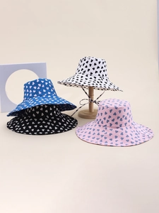Detail shot of heart-patterned bucket hats in blue, black, white, and pink with wind strings