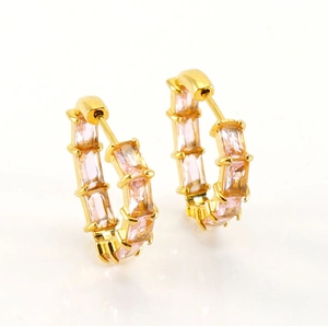 Detail of gold huggie hoop earrings with rectangular pink zircon pave setting