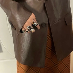 Detail of vintage beaded rings set styled with a leather jacket for a retro aesthetic