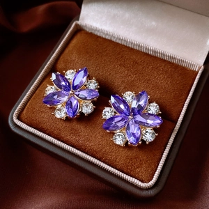 Detail of flower earrings with purple and clear gems in a brown velvet jewelry box