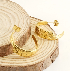 Detailed view of golden textured hoop earrings with irregular folded patterns on wood