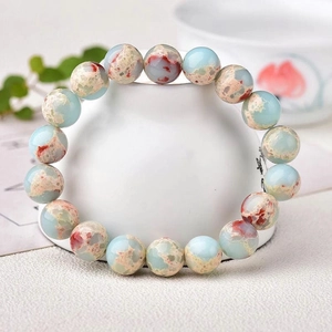 Detailed close-up of natural stone bead bracelet with blue and brown textures on ceramic