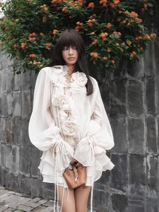 Detail of white chiffon top with large 3D flower decoration and ruffled hemline