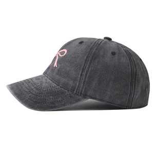 Dettaglio del ricamo fiocco rosa su cappello da baseball in denim grigio lavato