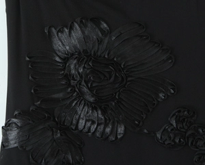 Macro shot of 3D ribbon flower applique on a black mesh fabric evening gown