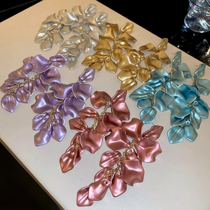 Detailed shot of long tiered petal tassel earrings in gold, silver, purple, and blue hues