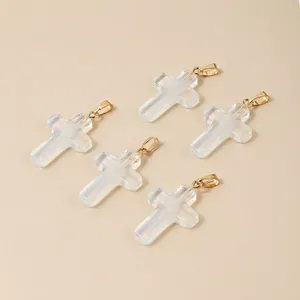Set of five elegant opal white cross pendants with golden metal clasps on beige background