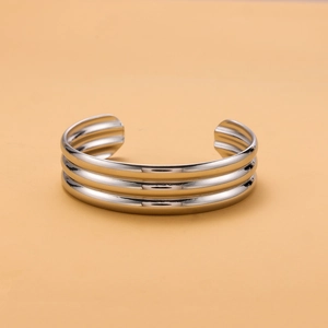 Macro detail of silver stainless steel open bangle with three-layer parallel ridge design