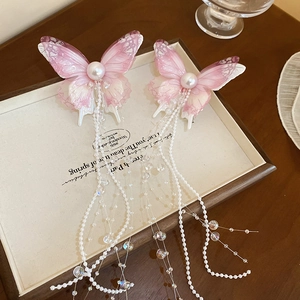 Detail showing pink butterfly hair clips with lace texture, pearls and long beaded tassels