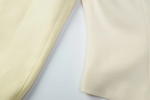 Detailed close-up of premium fabric texture and seamless stitching on a cream blazer