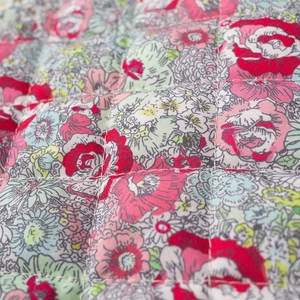 Detail of vintage floral print on quilted fabric with vibrant rose patterns and stitching