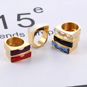Detail of square gold rings with colorful rectangle gemstones stacked for display