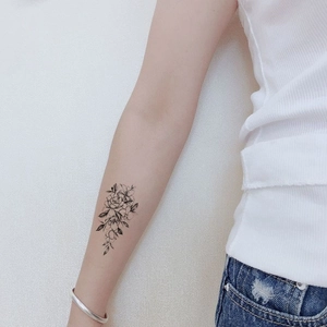 Minimalist black and white flower temporary tattoo sticker applied on the inner forearm