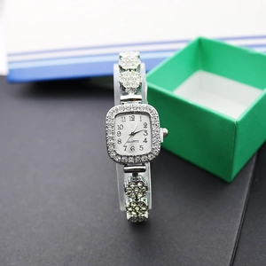 Détail d'une montre carrée argentée de luxe sertie de cristaux sur un support de vente