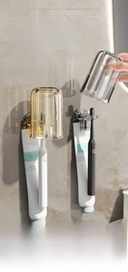 Macro detail of wall-mounted toothbrush holder with amber translucent cups and drainage system