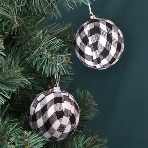 Classic black and white buffalo plaid Christmas ball ornaments hanging on a pine tree branch