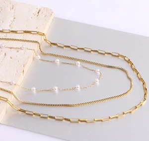 Detail of triple-layer 18K gold chain necklace with pearls on natural travertine