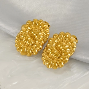 Gros plan sur des boucles d'oreilles ovales dorées avec texture spirale 3D sur soie