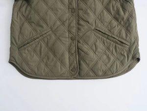 Close-up of military green quilted jacket featuring curved hem and slant pocket details
