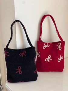 Détail de sacs tricotés rouges et noirs avec de grands nœuds brodés en relief 3D