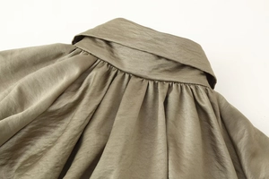 Detail of olive green satin bomber jacket showing pleated neckline and glossy texture