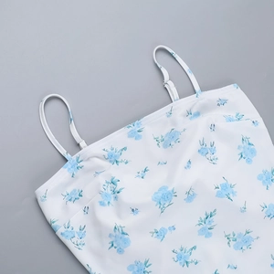Detail of adjustable thin spaghetti straps and blue floral pattern on white dress