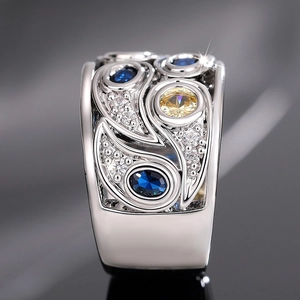 Gros plan sur bague en argent ajourée avec pierres bleues et gemme jaune centrale
