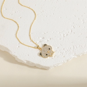 Macro detail of gold bear pendant with emerald cubic zirconia on white stone
