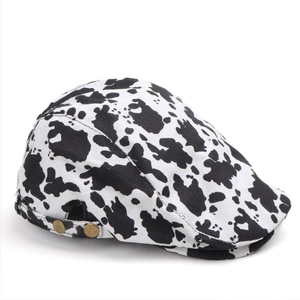 Detail of cow print newsboy cap showing twill cotton fabric and bronze side buckles