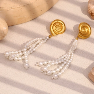 Detail of 18K gold snail stud earrings with elegant white multi-strand pearl tassels