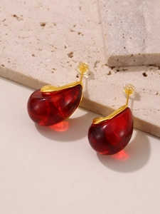 Macro shot of red enamel teardrop earrings with 18k gold plating on beige stone