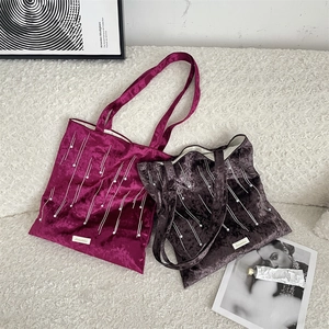 Detail of velvet tote bags with pearl embellishments and woven logo on furry surface