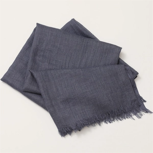 Close-up of dark grey cotton linen scarf featuring natural folds and fringe tassel edges