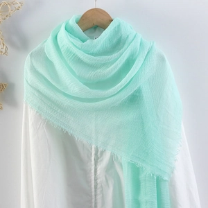 Close-up of mint green cotton linen scarf showing soft crinkle texture and frayed fringe edges